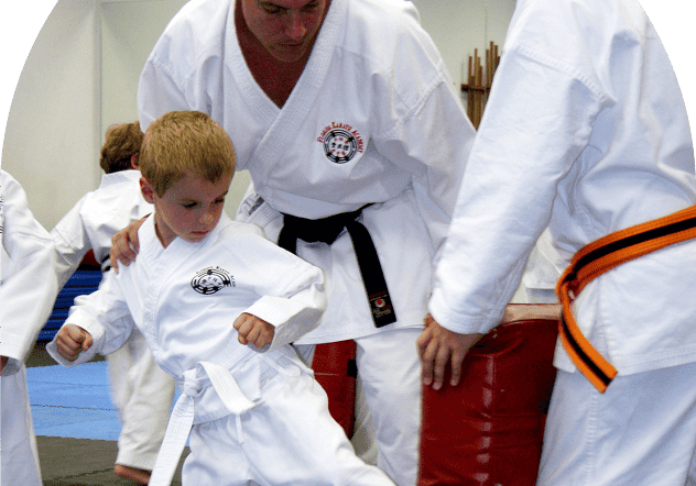 Child practicing karate kick with instructor